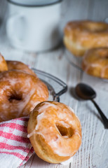 donuts on a tray with a cup and a teaspoon on a white wooden board