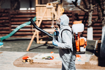 Specialist in hazmat suits cleaning garden and park, disinfecting and decontaminating surfaces. Coronavirus quarantine state of emergency