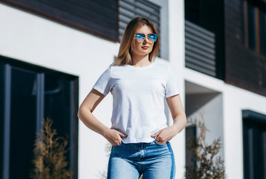 Girl wearing white t-shirt posing against street , urban clothing style. Street photography