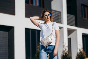 Young model girl in white t-shirt and glasses with waist bag