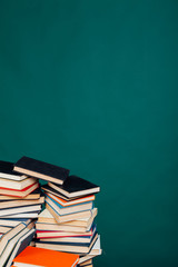 many stacks of educational books to teach in the school library on a green background