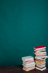 many stacks of educational books to teach in the school library on a green background