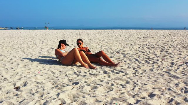 Beautiful young women in bikini sunbathe on paradise exotic beach with white sand by blue sea side on a bright sky in Malaysia