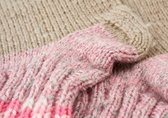 fragment of knitted socks from beige and pink woolen thread