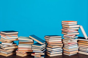 many stacks of educational books to teach in the library on a blue background