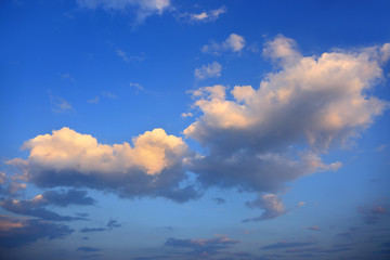 Puszyste chmury, obłoki na błękitnym niebie w czasie zachodu słońca.	