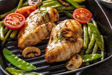 Close-up of healthy home cooked food, grilled chicken in a skillet with green vegetable, mushrooms and tomatoes