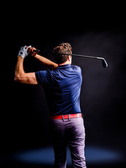 Close-up of a golf player intent on perfecting the swing isolated on dark background