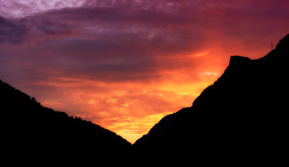 fiery sunset in the alpine valley after a summer storm