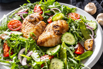 Close up of a healthy fresh salad with grilled chicken breasts and mushrooms on a plate