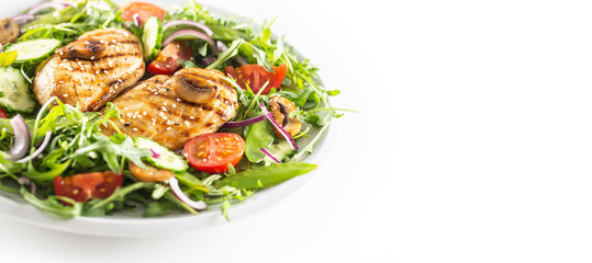 Healthy salad with grilled chicken topped with sesame seeds, rocket, spring peas, cherry tomatoes, sliced cucumber, grilled mushrooms and red onion, isolated on left half of the white background