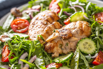 Close up of a healthy fresh salad with grilled chicken breasts and mushrooms on a plate