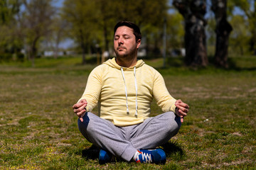 Naklejka na ściany i meble Man practicing Yoga in park. Meditation and zen relaxation in nature