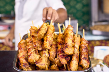 Man getting delicious chicken skewers from a barbecue.