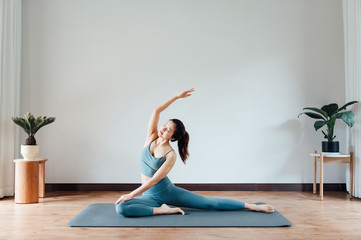 jonge Aziatische schoonheidsvrouw die thuis yoga doet