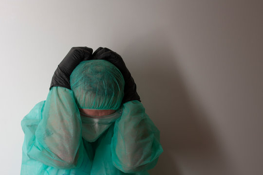 Male nurse, with plastic protective eyeglasses and respirator ffp2, cap, gawn,  with  personal protective equipment to protect against the rus covid-19 in ICU in hospital.