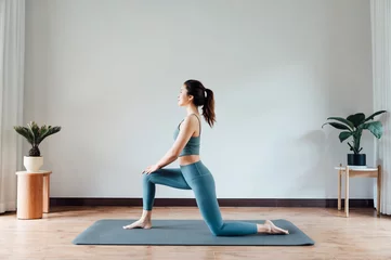 Foto auf Acrylglas Yogaschule junge asiatische Schönheitsfrau, die zu Hause Yoga macht