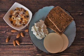 healthy breakfast of cottage cheese, cheese, granola, yogurt, bread, grapes and prunes on a wooden table