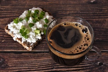coffee and a slice of rye bread with cottage cheese