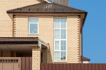 view of a private house with a large light brick window through a fence