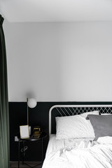 Stylish two tone green and white  bedroom corner with decorative frame and plant in scandinavian style apartment