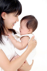 泣いている赤ちゃんを抱く笑顔のお母さん。育児、愛情イメージ
