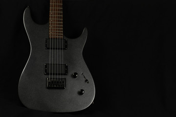 Obraz na płótnie Canvas Grey electric guitar on a black background, copy space