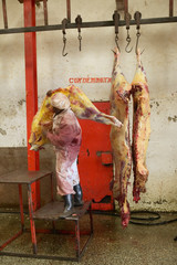 Man moving Cow carcass from scale being weighed at Nyongara slaughterhouse in Nairobi, Kenya, Africa