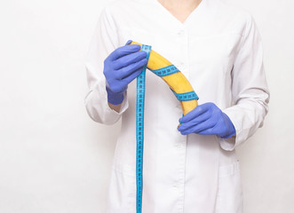 Dr. plastic hiururg holds a banana in his hands. The concept of plastic surgery for penis enlargement, phalloplasty, erection © HENADZY