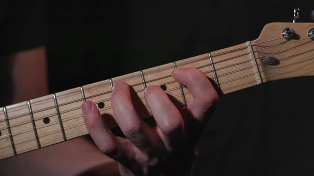 Male Guitar player plays blues style riff on guitar, close up on hand.