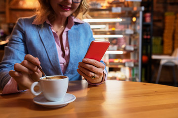 Woman having coffee in cafe and using mobile phone