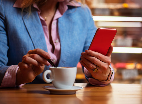 Woman having coffee in cafe and reading something on her mobile phone