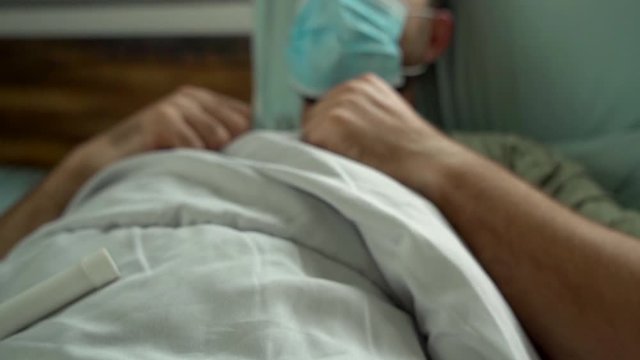 Man laying in bed being sick wearing surgical mask