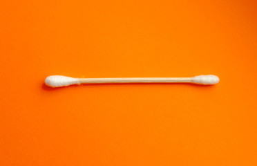 Wooden ear stick close-up. Zero waste and recycling. Eco friendly product. Banner template with copy space on the orange background. Organic cotton stick for self hygiene. No plastic.