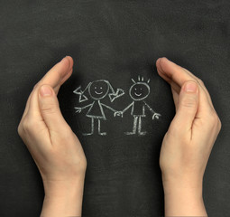 Hands protect children drawn on blackboard with chalk. Concept for International Children's Day, June 1