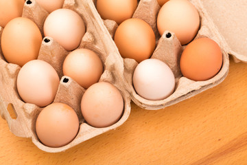 brown chicken eggs in an open cardboard box with eggs on a wooden table. Natural healthy food.