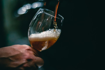 bartender hand at beer tap pouring a draught beer in glass serving in a restaurant or pub