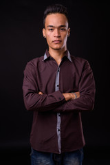 Portrait of young handsome Indian businessman with arms crossed