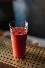 Strawberry and red bell pepper smoothie in the glass. Cold blue background.
