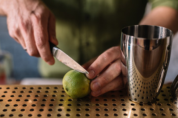Bartender slicing lime with knife in the bar.