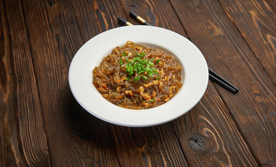 Asian food. Fried glass кice noodles with meat and vegetables. Chinese glass rice vermicelli fried with meat and tomatoes. Korean funchoza cellophane noodles