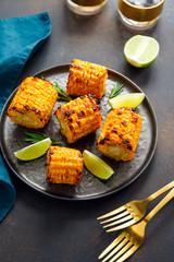 Roasted or grill corn cob with olive oil and salt on a black plate.