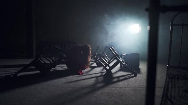 a girl in a red straitjacket in a psychiatric clinic sits on the floor among the chairs around