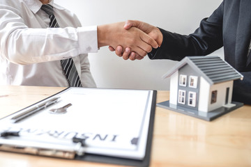 Businessmen and brokers real estate agents shake hand after completing negotiations to buy houses insurance and sign contracts. Home insurance concept