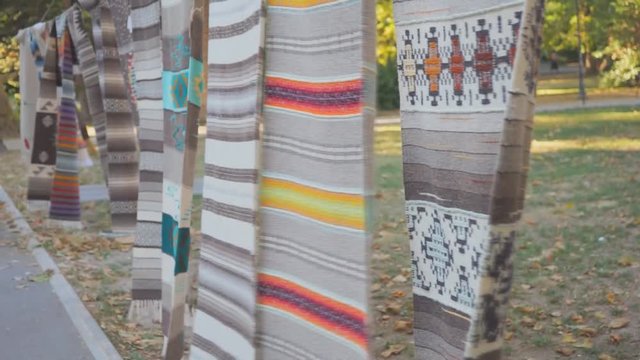 Hand-made colored carpets hang on a rope and sway from the wind