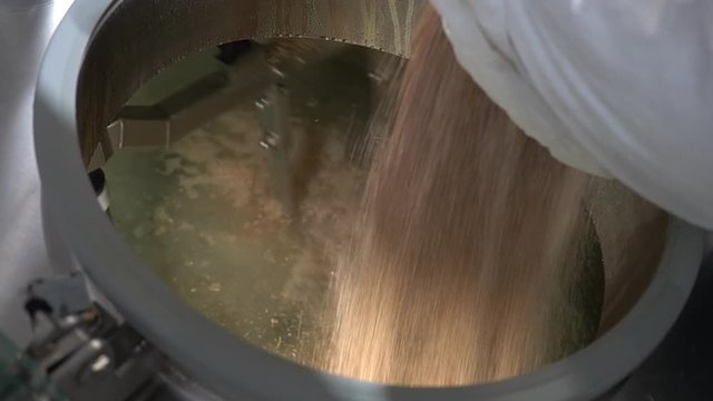 Brewer Pours Malt From Bag Into Beer Brewing Tank. Craft Beer.
