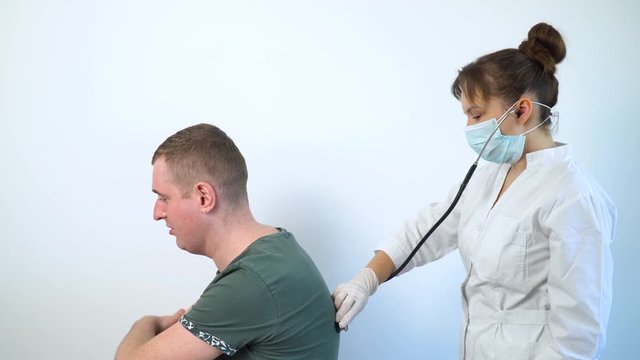 Female doctor using a stethoscope listens to the lungs of a sick male patien at a medical visit in the hospital. Health care concept. Detection covid-19