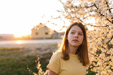 Portrait of young beautiful blonde woman near blooming tree with white flowers on a sunny day. Spring, girl near a flowering tree.beautiful girl in a yellow t-shirt near a flowering tree