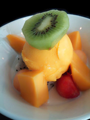 Fresh kiwi on mango ice cream And another fresh fruit closeup, isolated in black background