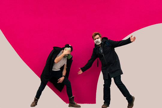 posing teenager have fun about corona virus theme in black cloth and medicine mask in painted vivid pink and white concrete wall background hipster style photography, irresponsible behavior